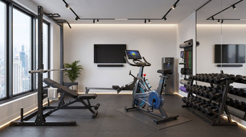 A complete layout schematic of a modern, compact apartment gym showing the spatial footprint dimensions of a smart upright stationary bike and a set of weights