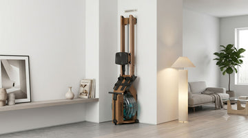 A premium Wenoker RW211-50 wooden water rowing machine stored completely upright and flush against a minimalist living room corner wall
