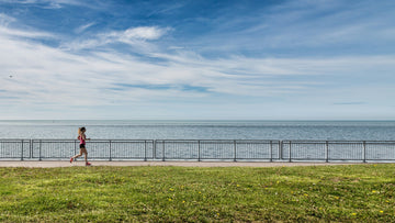 A runner enjoying a scenic trail run, demonstrating proper running form and engagement of full body muscles.